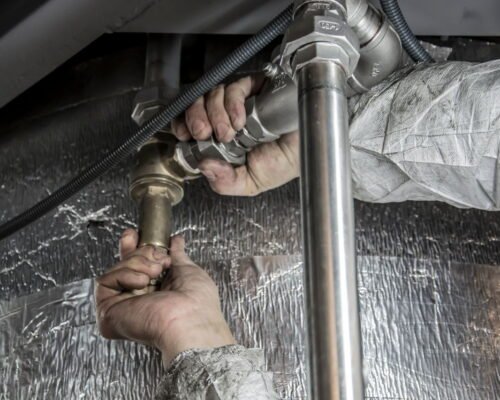 Handen van een loodgieter die stalen leidingen monteren (1) Handen van een loodgieter die stalen leidingen monteren